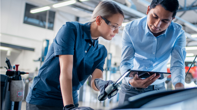 Delphi Experts using a tablet and an inspection lamp to investigate under the bonnet of a car.